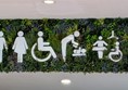 Image of toilet symbols surrounded by green foliage