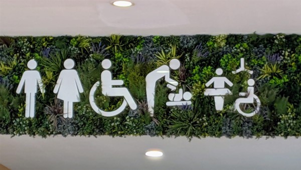 Image of toilet symbols surrounded by green foliage