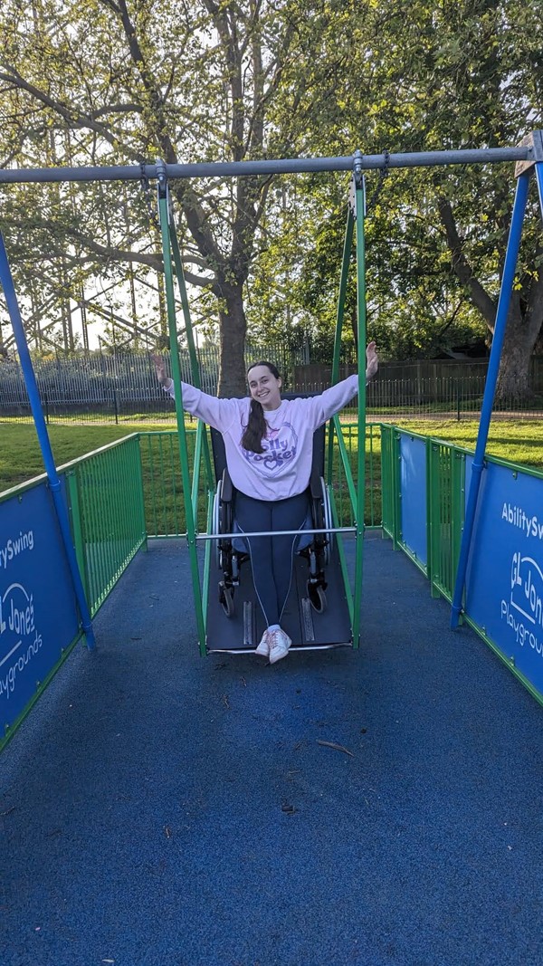 Image of reviewer on wheelchair accessible swing.