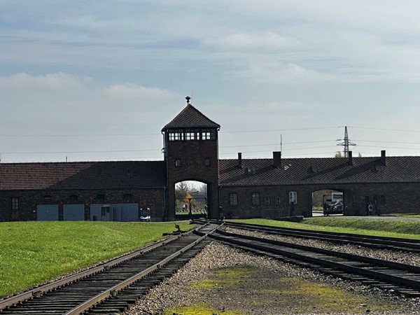 A colour photograph of the tracks leading through the gates and into the Birkenau camp