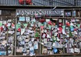 Image of the shrine, white letters on a black sign read "Ianto's Shrine" and there are plenty of pictures and tributes.