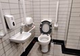 Accessible toilet cubicle, showing the complete absence of wheelchair transfer space.