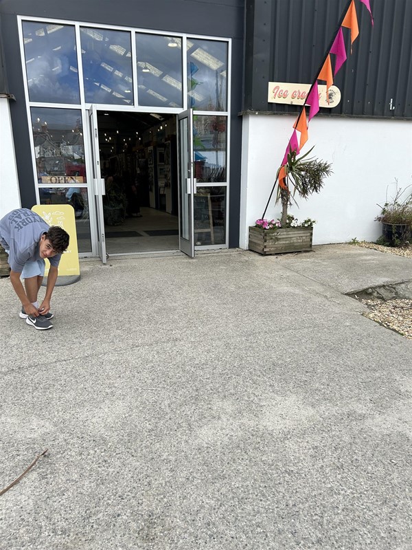 Imafe of someone doing up a shoelace outside a building