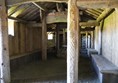 Inside the longhouse with wooden pillars and benches around the edge.