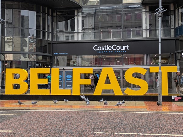 Image of entrance to CastleCourt set behind a large yellow 3D Belfast
