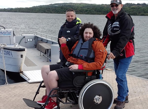 Image of a group of men standing next to a person in a wheelchair