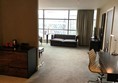 Large hotel bedroom with couch and large window