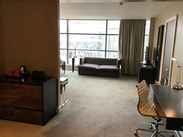 Large hotel bedroom with couch and large window