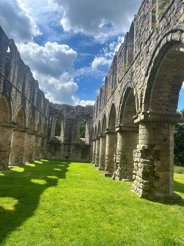 Image of a stone building with arches and grass