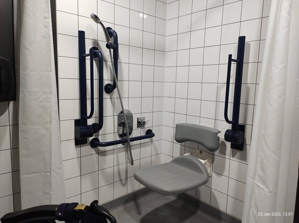 Shower and shower chair with fold away rails available in the accessible toilet