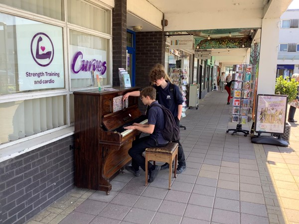 Picture of people playing a piano outside