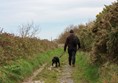 Hubby and dog walking down a muddy cliff path.