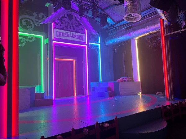 A small stage lit up in rainbow colours