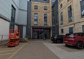 Image of entrance to the hotel, on the right there are parking spaces