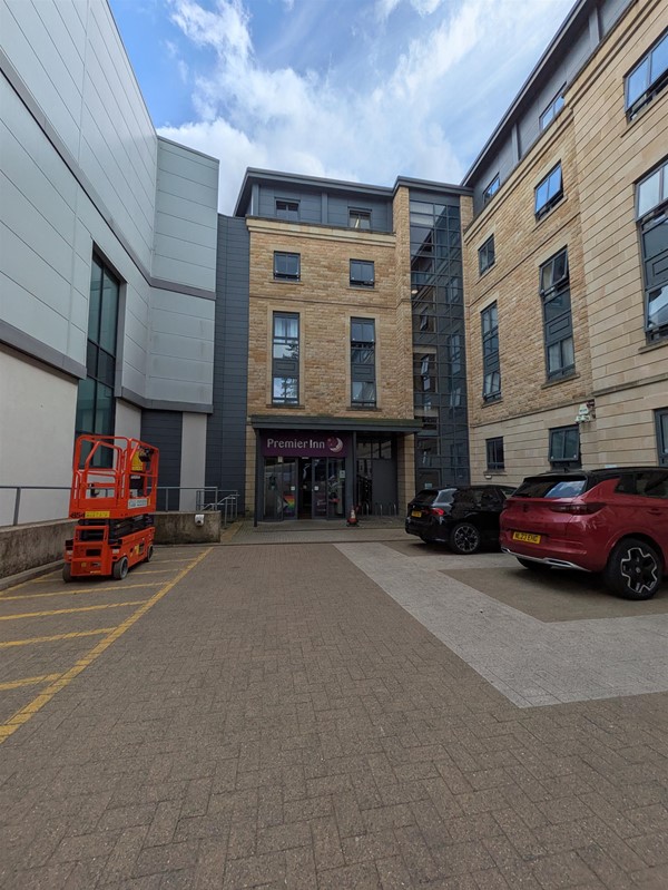 Image of entrance to the hotel, on the right there are parking spaces