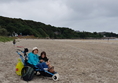 Using the beach wheelchair on Marble Hill Strand with dunes and wooded cliffs behind