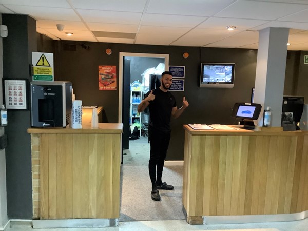 Man standing at reception doing a double thumbs up sign