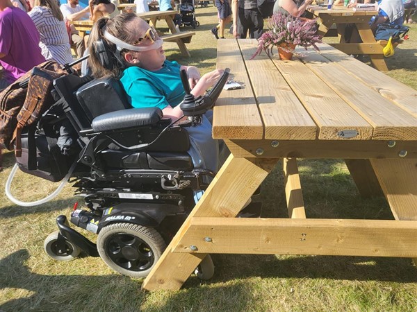 Image of Claire sitting at one of the wheelchair accessible picnic bench.