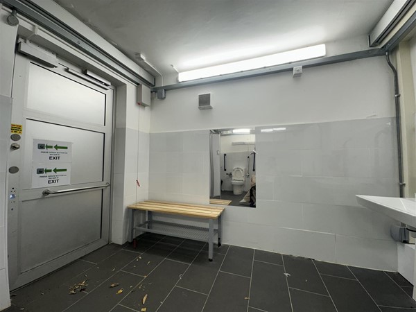 Image of large accessible Changing Places toilet with small bench and wall-mounted mirror