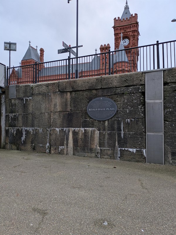 Image of a grey plaque on a brick wall with the writing Roald Dahl Plass