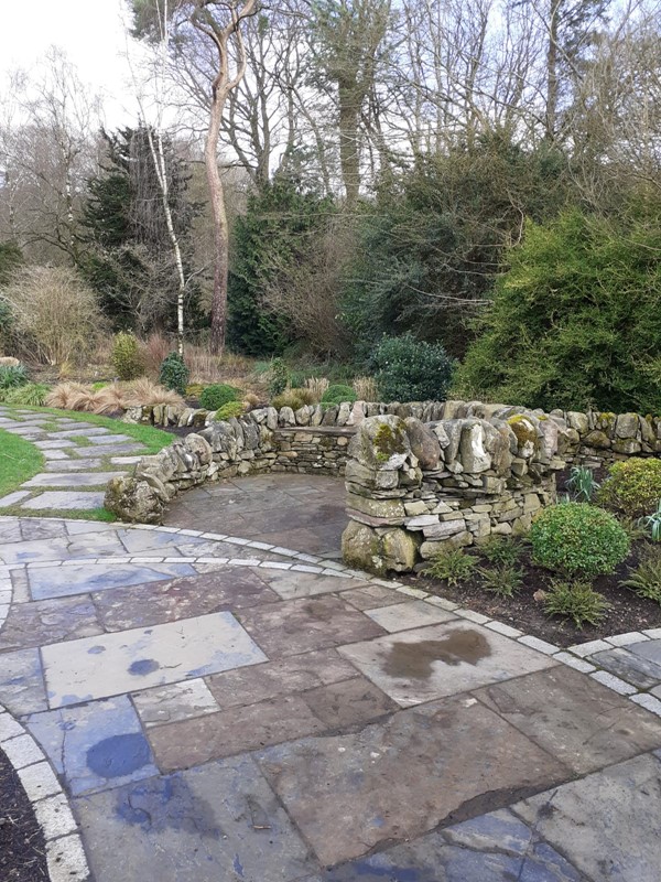 A drystone wall next to a flat path. In the left corner you can see the path to the garden (hard to go over with a wheelchair) (garden of contemplation)