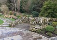 A drystone wall next to a flat path. In the left corner you can see the path to the garden (hard to go over with a wheelchair) (garden of contemplation)