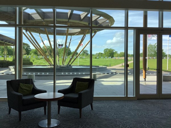 Picture of a table with two chairs looking out through a window to a sculpture