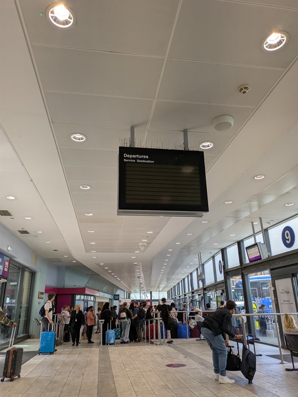 Image of overhead signage - which is blank. A queue of people are waiting to board from stance 7