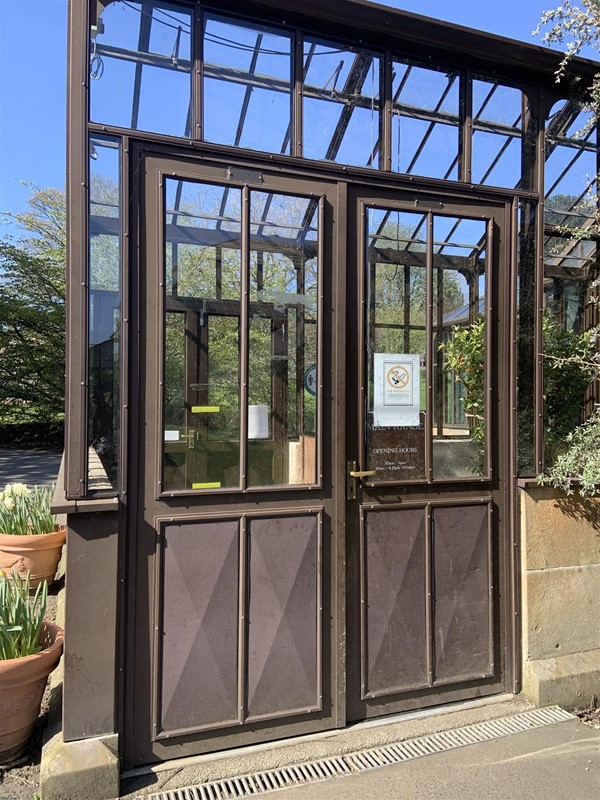 Image of double doors at the entrance to the greenhouse. The door on the right has a lever handle.