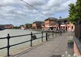 Picture of a path by the water leading to some red brick buildings