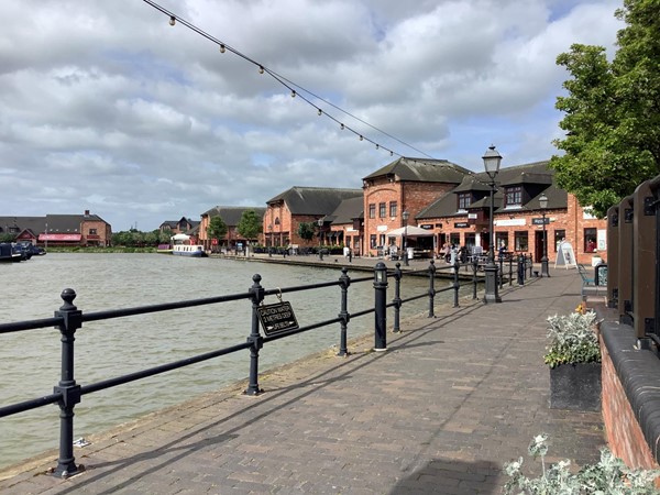 Picture of a path by the water leading to some red brick buildings