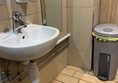 Image of sink, mirror, bin in corner and space on floor