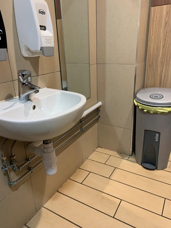Image of sink, mirror, bin in corner and space on floor