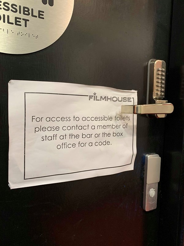 Close up of sign on accessible toilet that says 'For access to accessible toilets please contact a member of staff at the bar or the box office for a code'