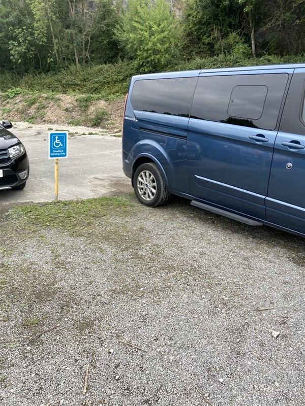Image of a blue van and a disabled parking sign